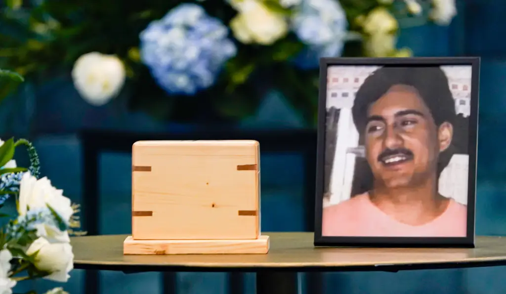 A photo of Jeffrey A. Jones next to his remains in a wooden urn.