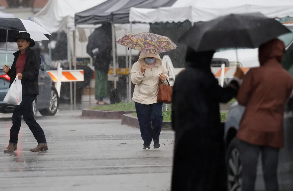People at a Pasadena farmer's market during an atmospheric river storm.