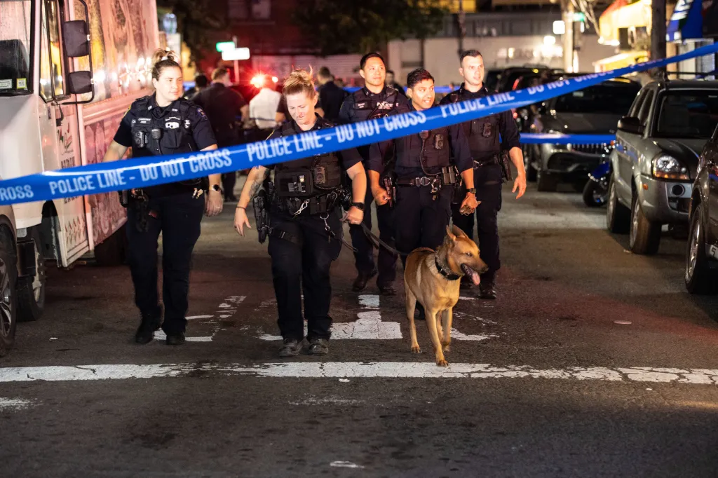 Police officers with a K9 unit at the scene of a shooting in Queens, New York.