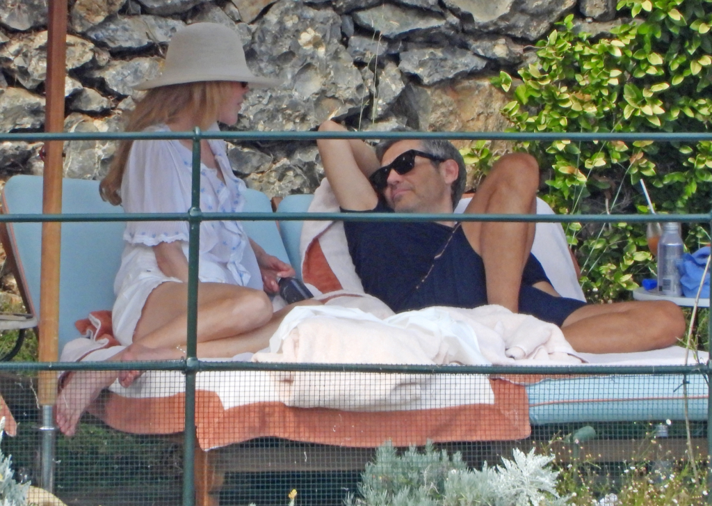 Nicole Kidman and a man relaxing on sun loungers poolside.
