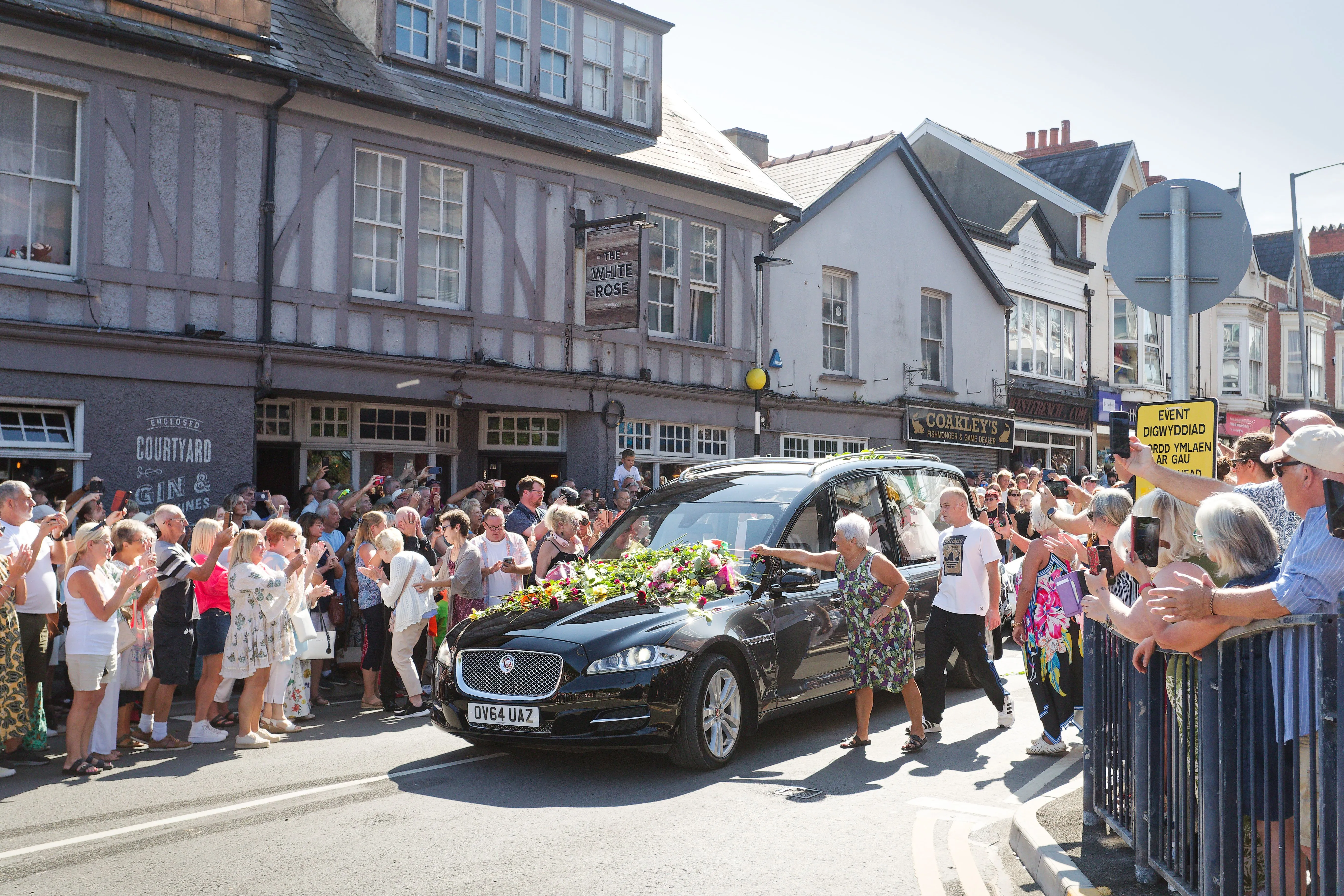 Fans lining a street to pay respects to Bonnie Tyler as her hearse drives by.