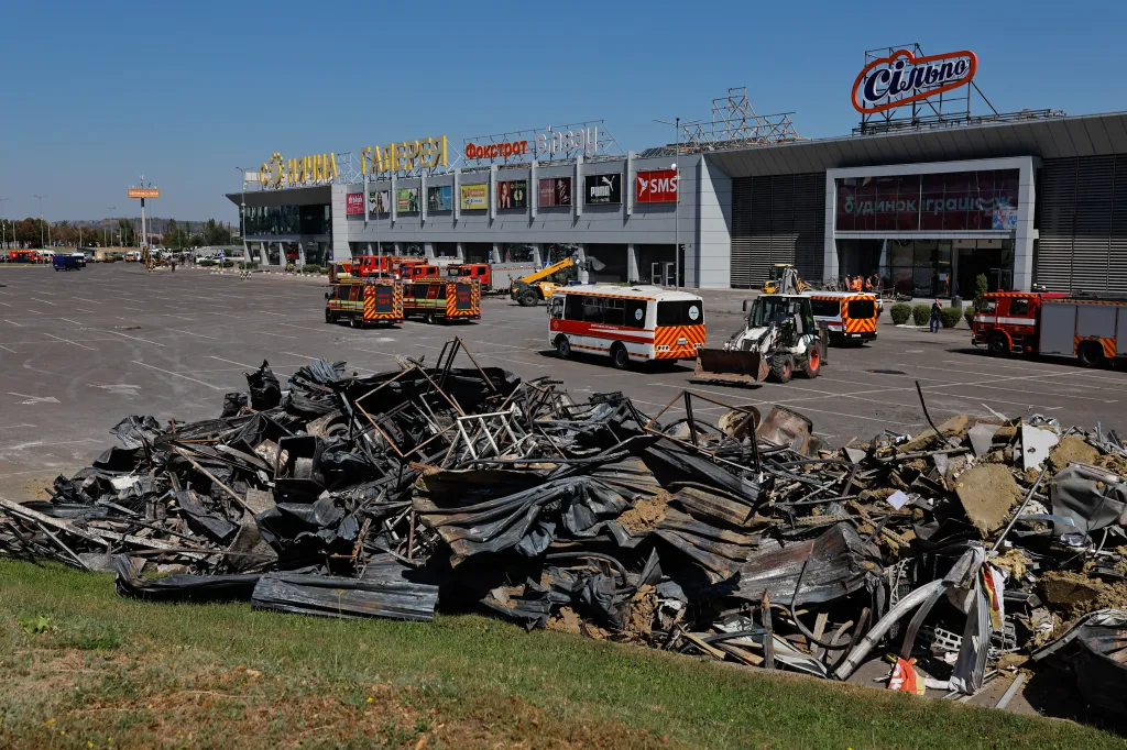 Debris from a damaged shopping mall in Kryvyi Rih after a Russian strike, with emergency vehicles and construction equipment clearing the area.