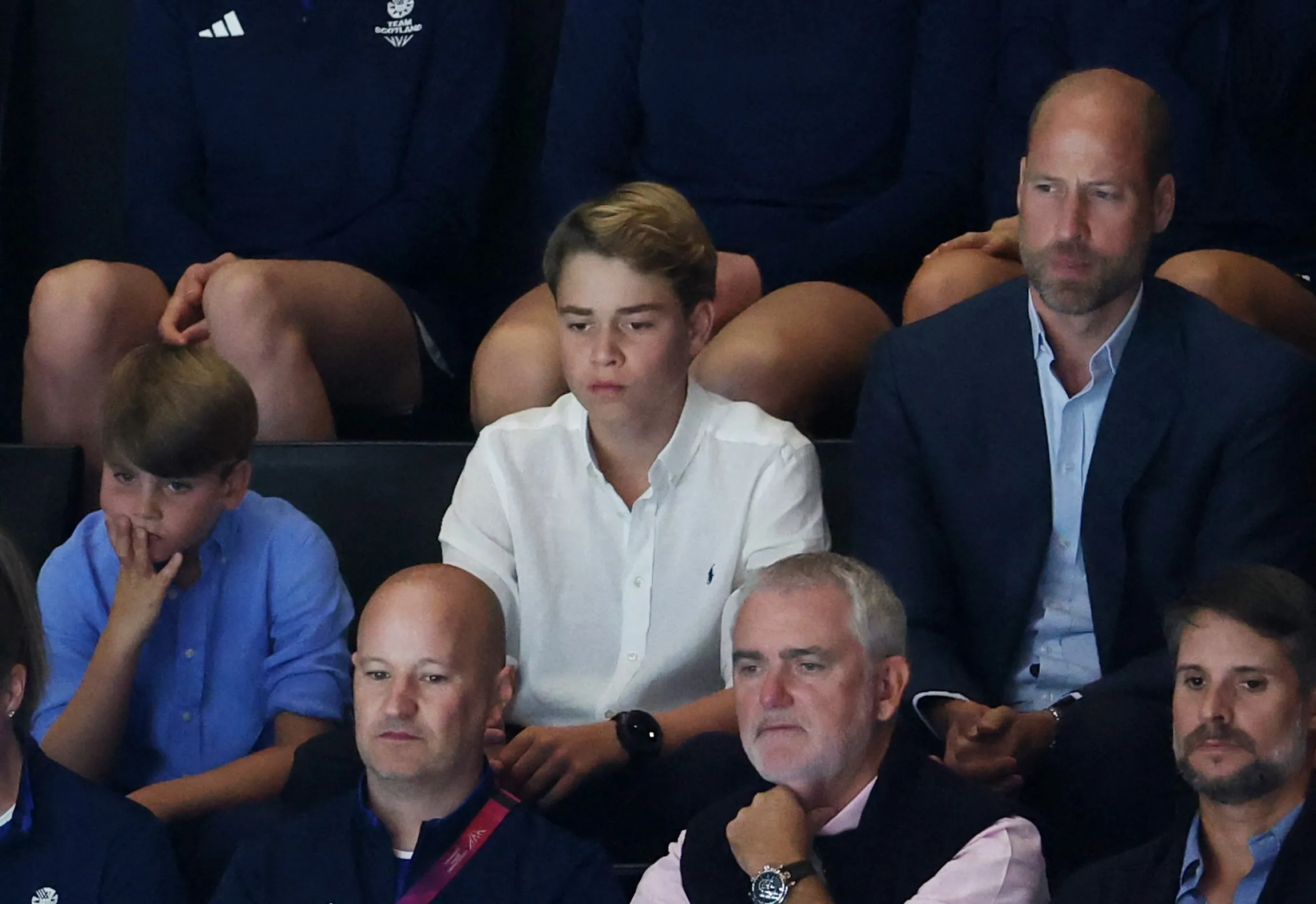 Prince William, Prince George, and Prince Louis in the stands during a netball match.
