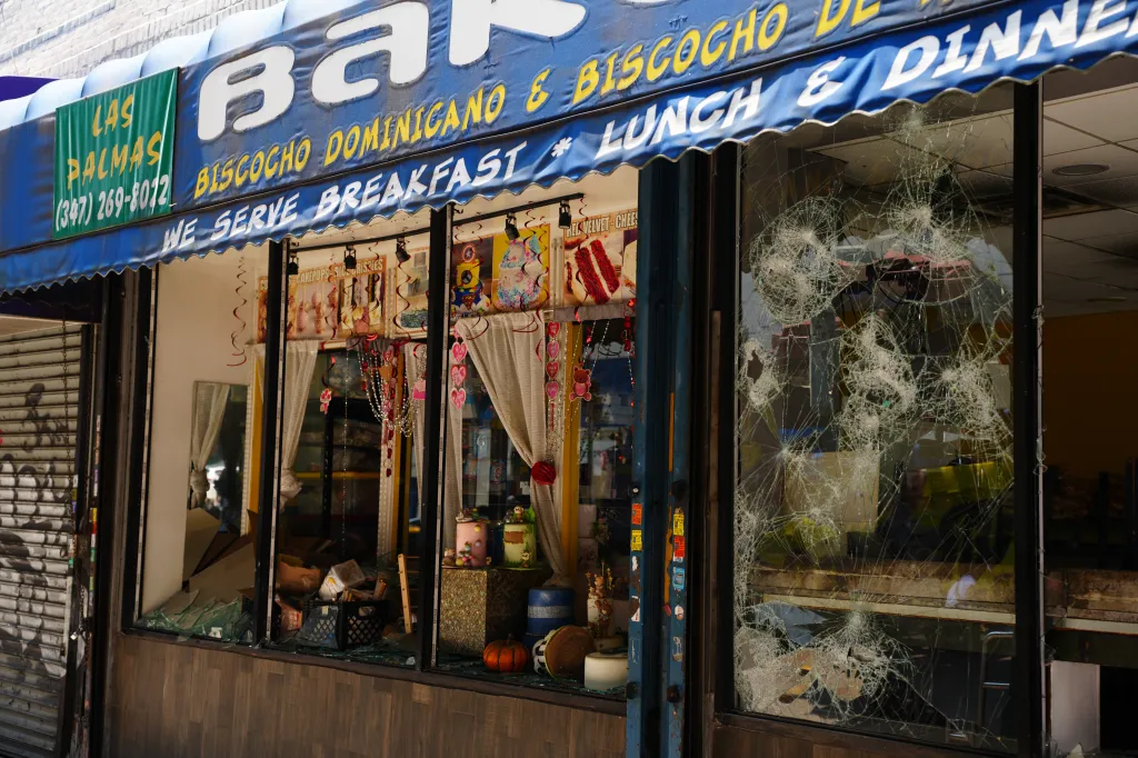 Passersby look at damage to delis and surrounding stores on Wednesday, August 12, 2026, in the Bronx, N.Y. A man was rushed to the hospital with serious burn injuries after a two-alarm fire broke out Tuesday night and spread to multiple businesses.