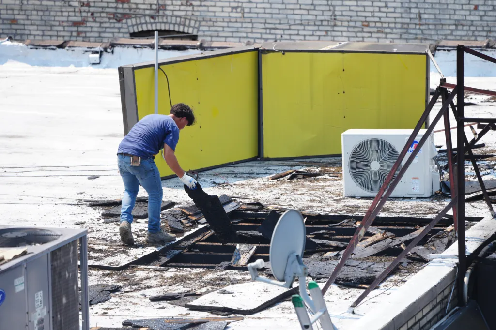 Workers clear debris from the roof of a deli on Wednesday, August 12, 2026, in the Bronx, N.Y. A man was hospitalized with serious burn injuries after a Tuesday night fire that witnesses said began when Molotov cocktails were thrown inside the deli.