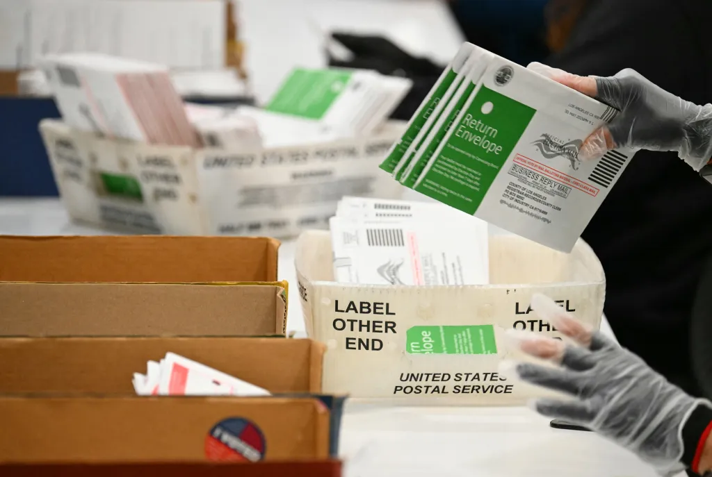 An election worker wearing gloves processes mail-in ballots at the Los Angeles County Ballot Processing Center.