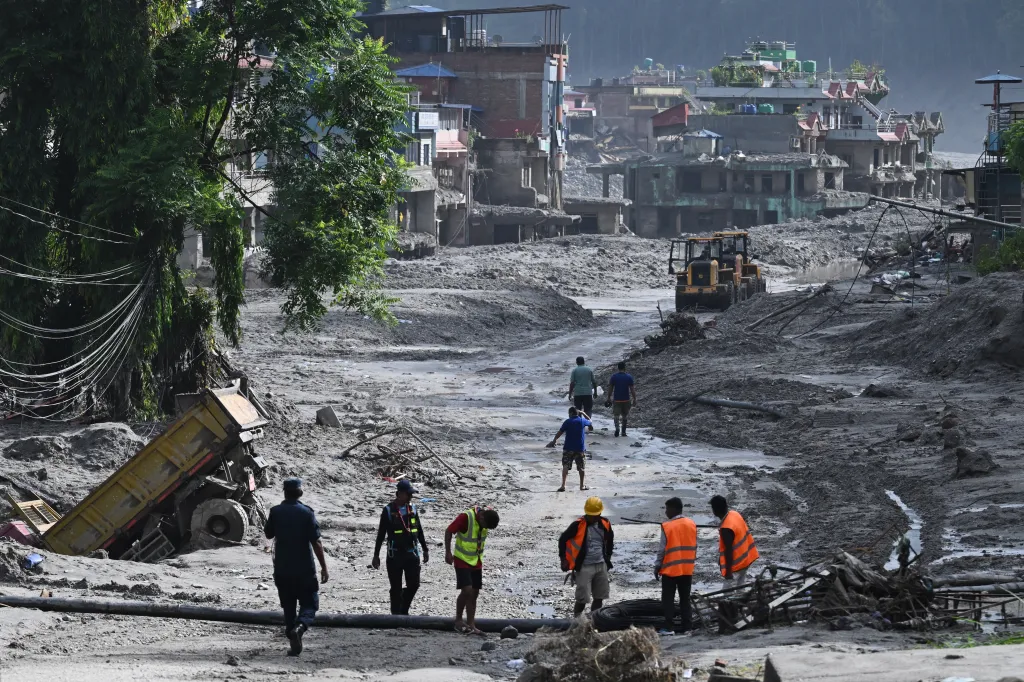 Rescue workers search for survivors in the muddy debris of a flood-ravaged town in Nepal.