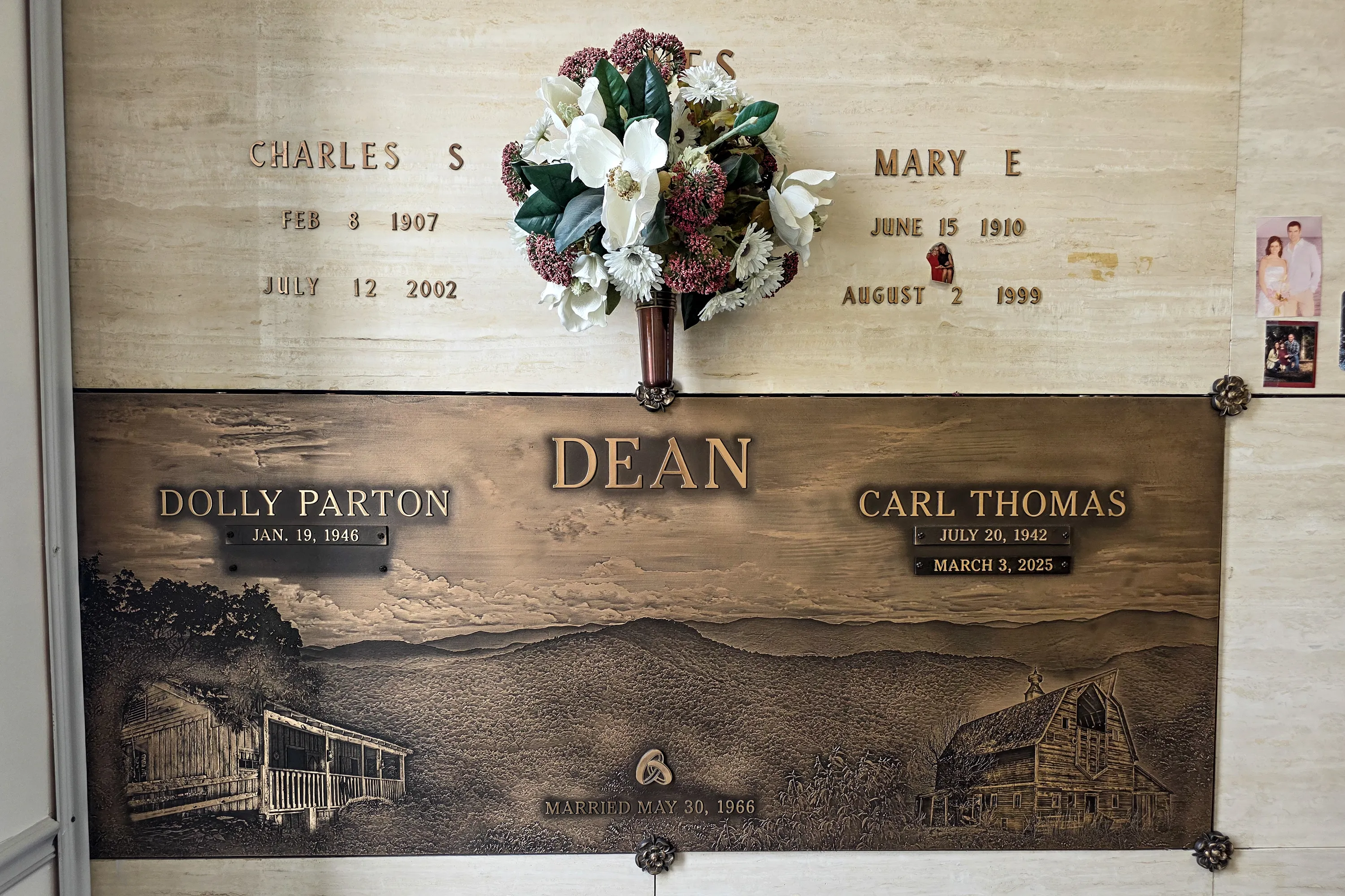 Bronze memorial plaque for Dolly Parton and Carl Thomas Dean at Woodlawn Roesch-Patton Funeral Home, depicting a mountain scene with a cabin and a barn, and a floral arrangement above.