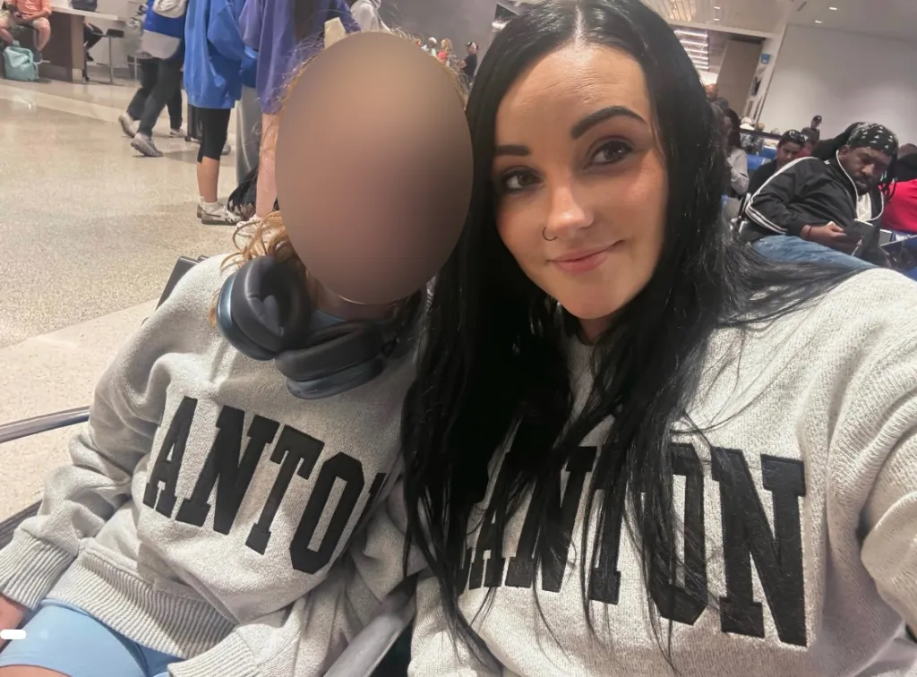 Bridget with her child, whose face is blurred, both wearing gray sweatshirts.