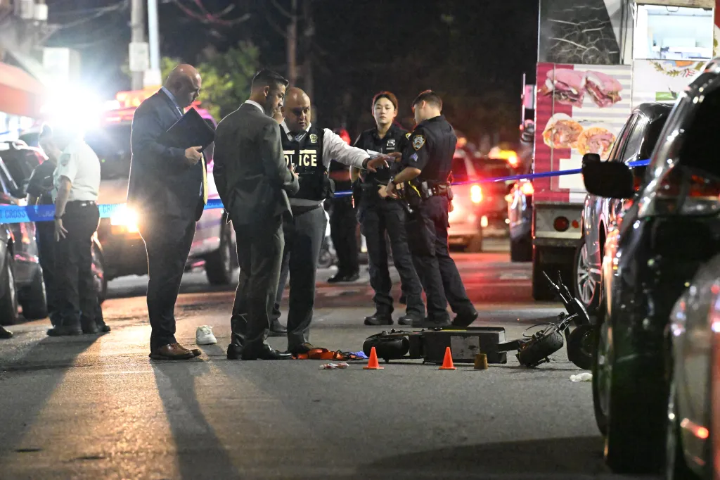 NYPD officers and detectives investigate a shooting scene at night on 39th Avenue and 104th Street in Queens, New York.