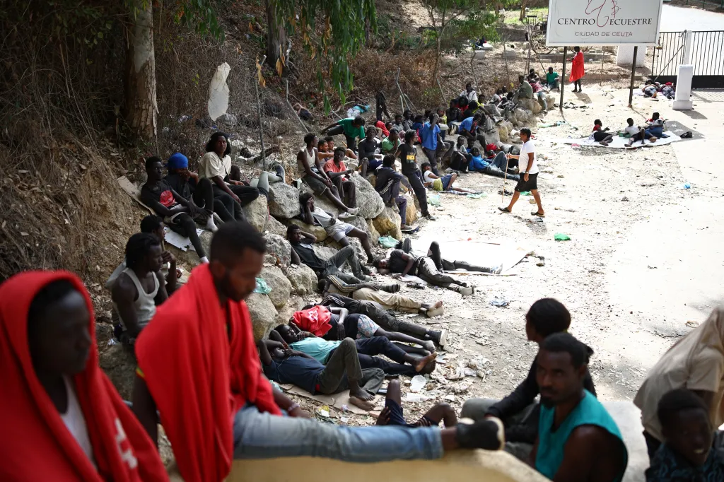 Migrants resting outside the CETI short-stay migrant center in Ceuta.