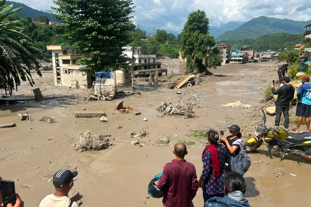 Residents look at houses partially submerged in muddy floodwater in Nepal's Nuwakot district.