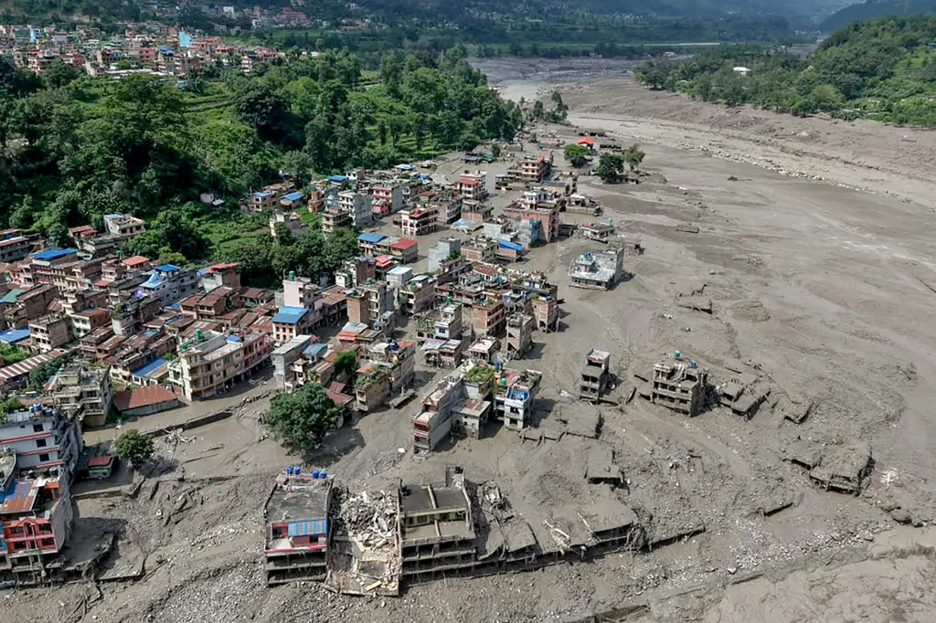 Aerial view of houses partially submerged in muddy water and surrounded by a dried, wide riverbed in Trishuli Bazar, Nepal, after flash floods.
