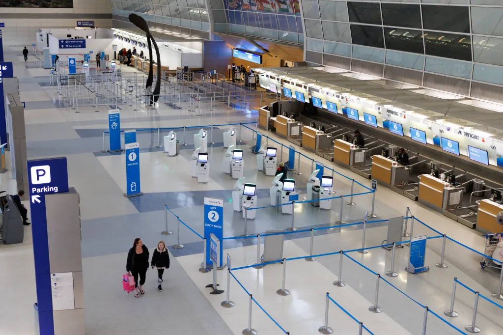 Two travelers walk through an empty terminal at Dallas-Fort Worth International Airport on Jan. 24, 2026.