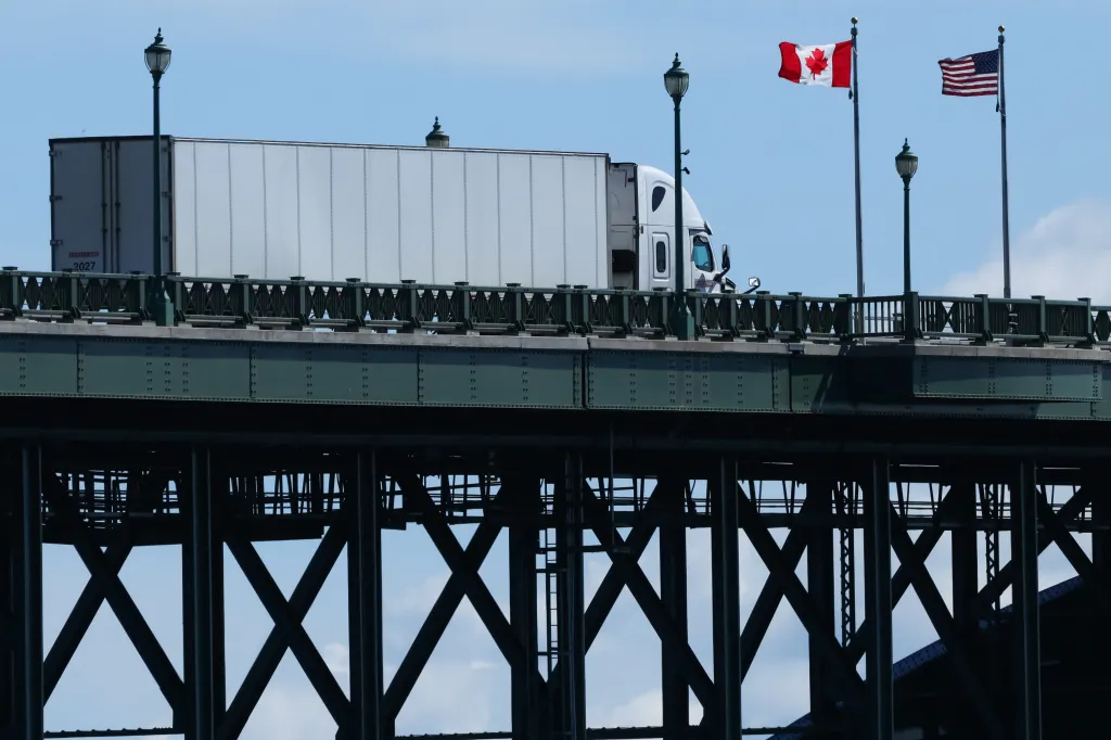 A truck crosses the Peace Bridge, with Canadian and US flags flying above.