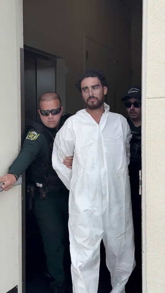 Raul Lionel Vazquez, 26, in a white jumpsuit, escorted by Orange County Sheriff's deputies after his arrest for second-degree murder.