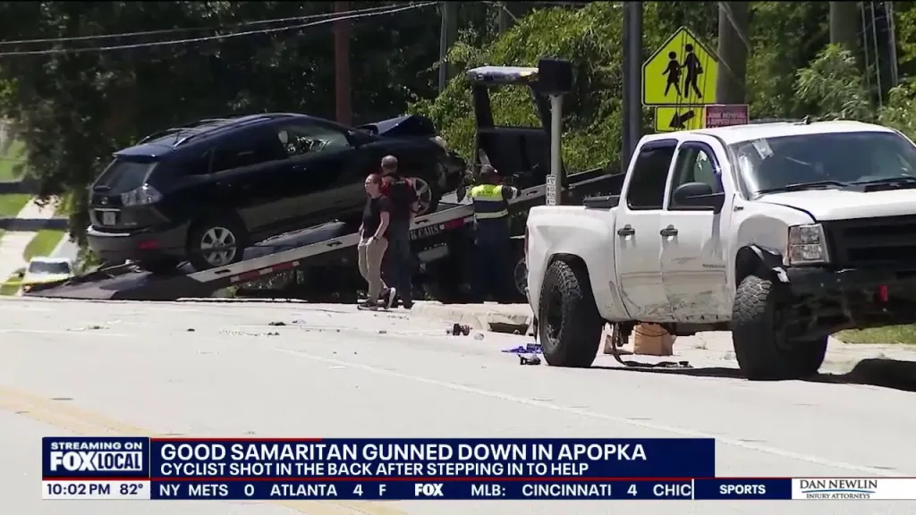 A black SUV on a tow truck and a white pickup truck, with news text about a good Samaritan shot in Apopka.