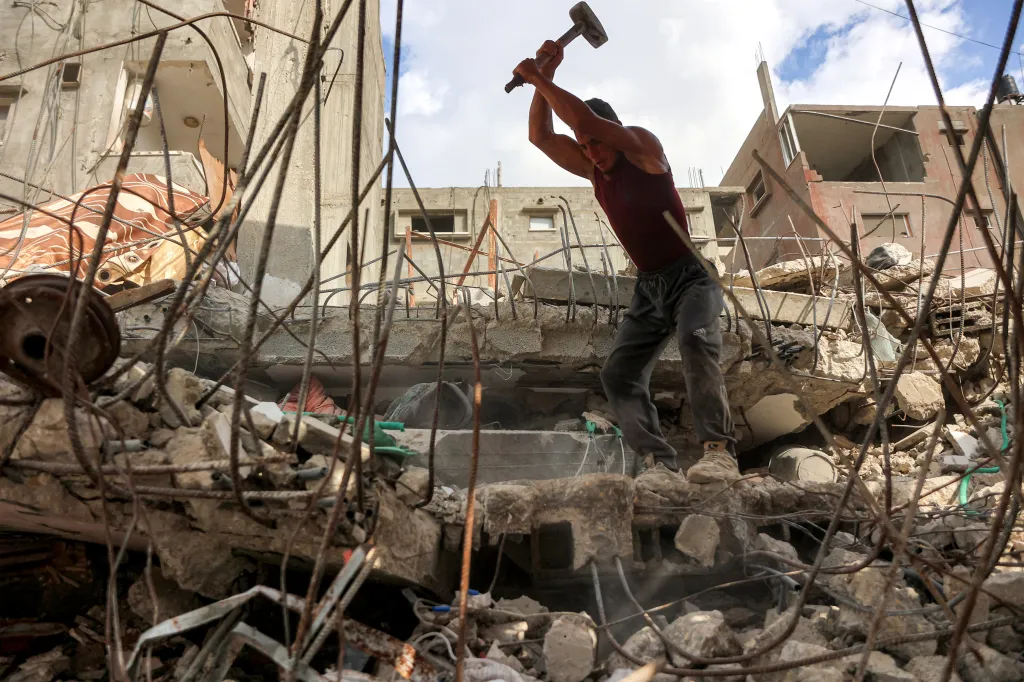 A man using a sledgehammer to break rubble in a destroyed building in Gaza City.
