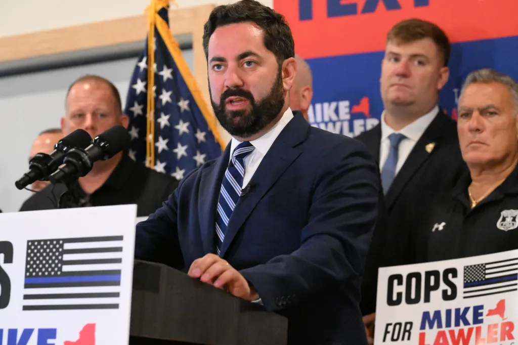 US Representative Mike Lawler speaks at a podium with police association presidents behind him, and 