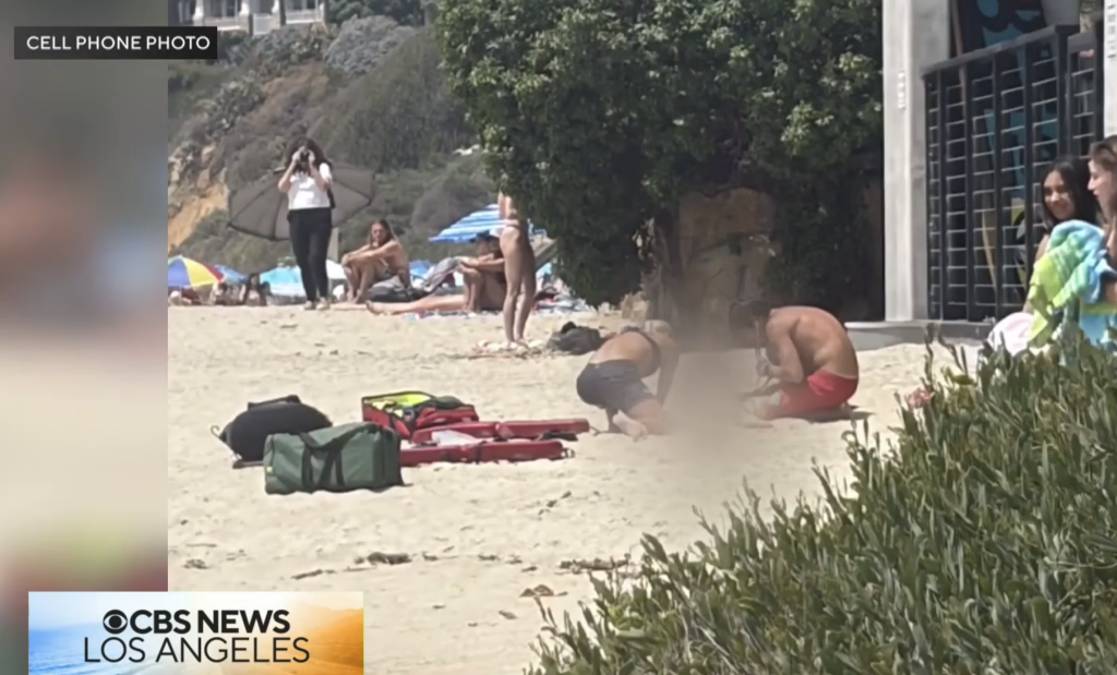 A crowded beach with people on the sand and rescue equipment in the foreground.
