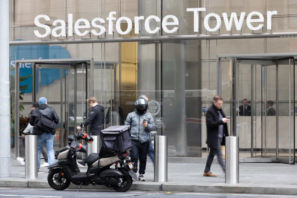 Pedestrians and a parked scooter with a delivery bag outside Salesforce Tower.