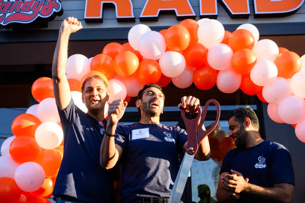 Three men, Saeed Uzzaman, Ausaf Masud, and Adeel Siddiqui, celebrating the opening of Randy's Donuts in Santa Clara.