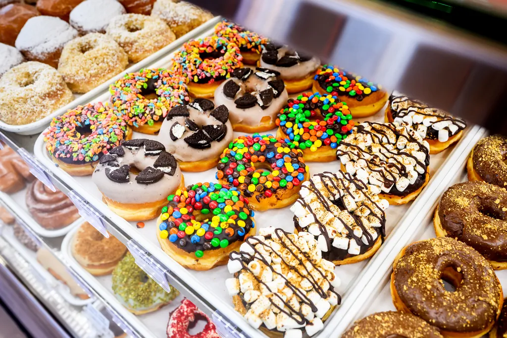 Assortment of donuts with various toppings on display shelves.