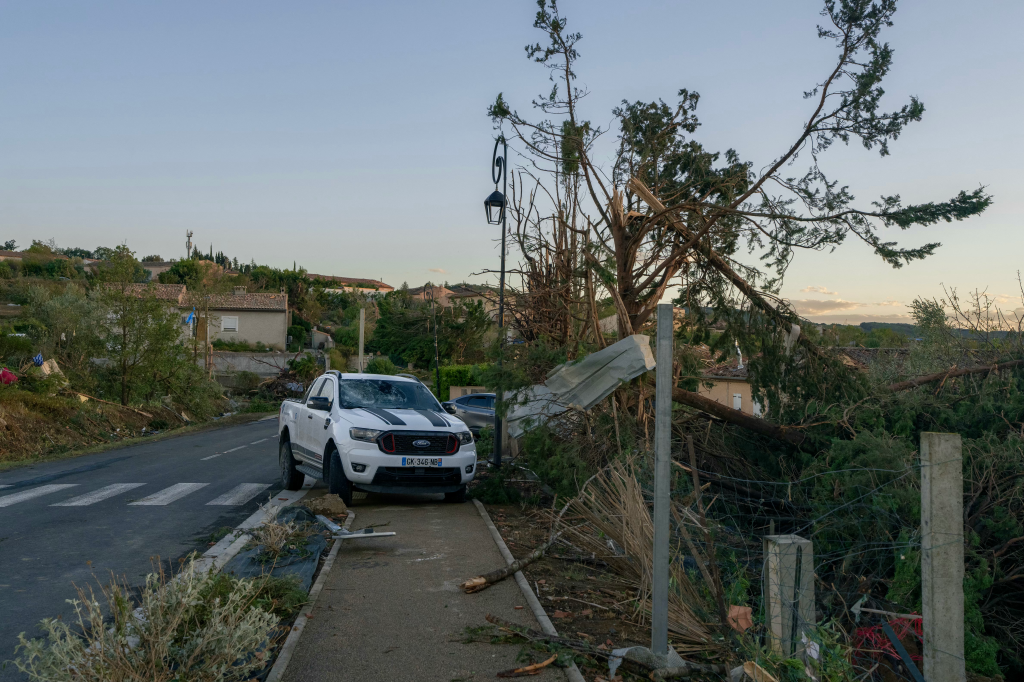 A damaged white truck and fallen trees on a street in Pomas, France, after a tornado.