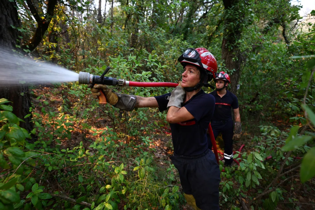 A firefighter sprays water on remaining hot spots after a wildfire.