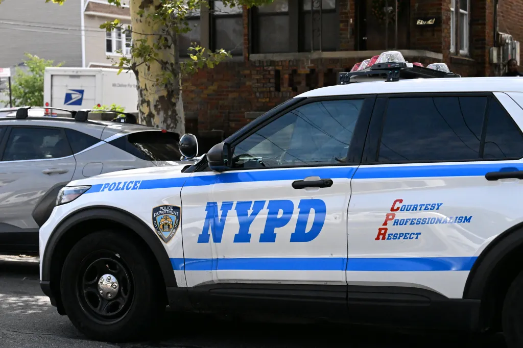 A close-up of a white NYPD police car with blue and red lettering.