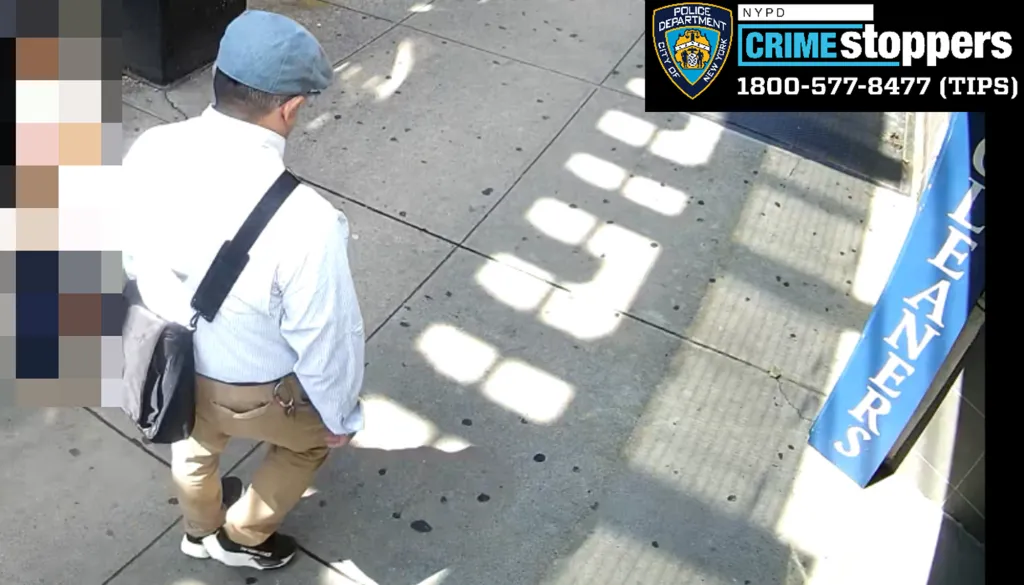 Surveillance image of a man in a light blue cap, white shirt, and tan pants walking on a sidewalk.