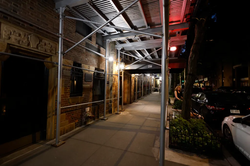 The exterior of 210 E. 73rd Street in Manhattan's Upper East Side, covered by scaffolding, at night.