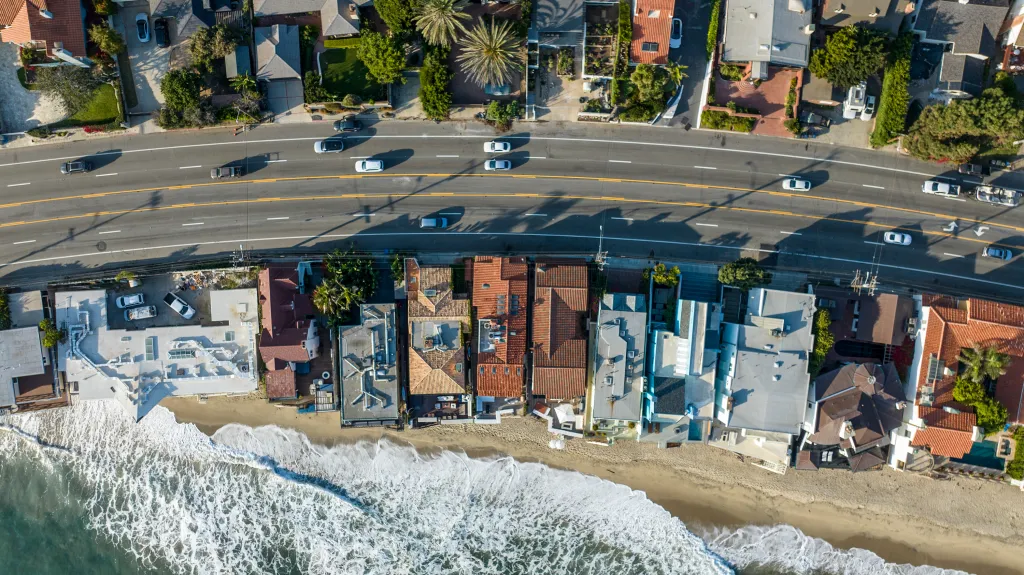 Aerial view of the 21600 block of Pacific Coast Highway, a four-lane road, with houses on both sides and the ocean to the left.