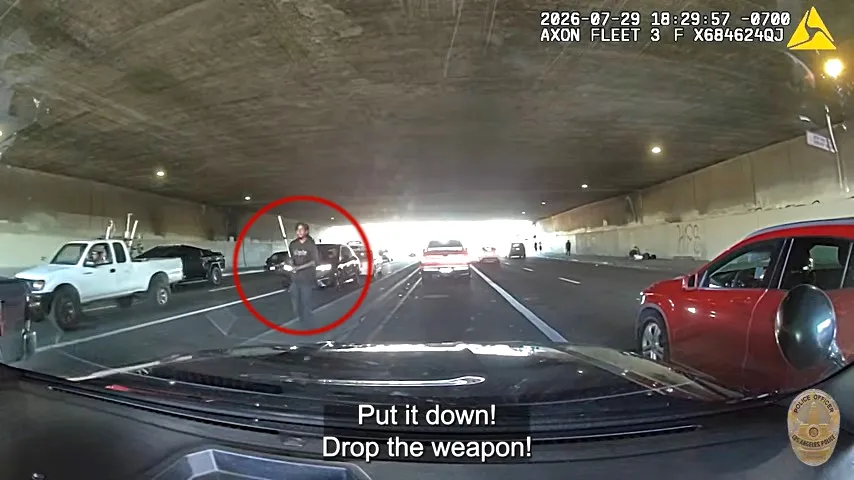 Dash cam footage shows a man with a weapon, circled in red, standing on a street as police tell him to 