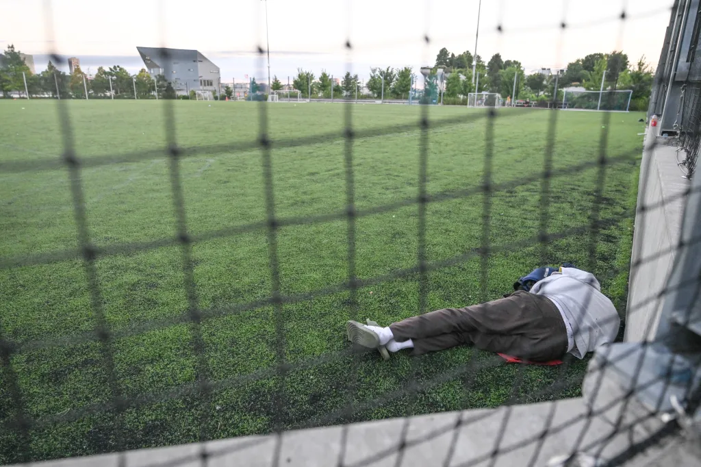 A person sleeping on a soccer field at Pier 53 Gansevoort Peninsula in Hudson River Park in New York City.