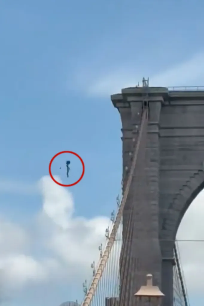 Person falling from the Brooklyn Bridge, highlighted by a red circle, with the bridge's stone tower and cables visible on the right.