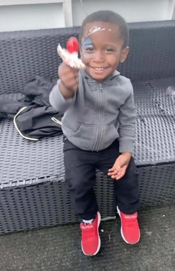 Deshawn Fleming, a 3-year-old boy with face paint, smiling and holding a lollipop.