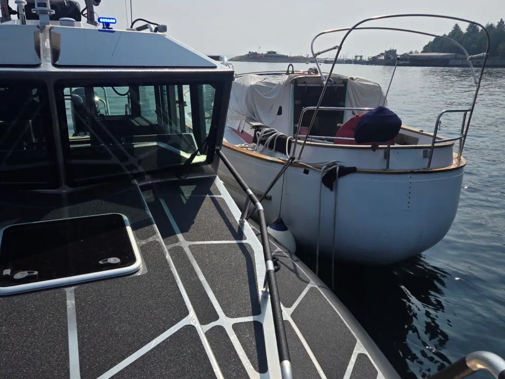 A rescue boat docked next to an abandoned sailboat.