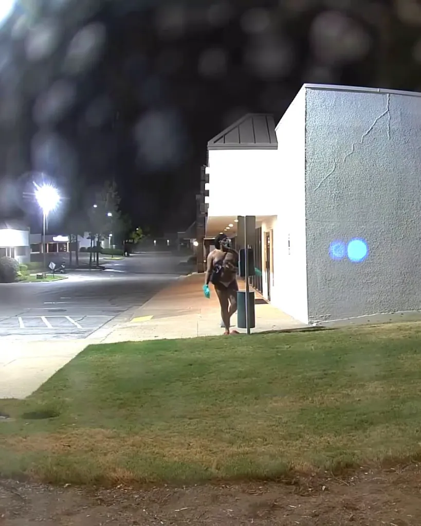 Surveillance photo of a person walking near a building at night.