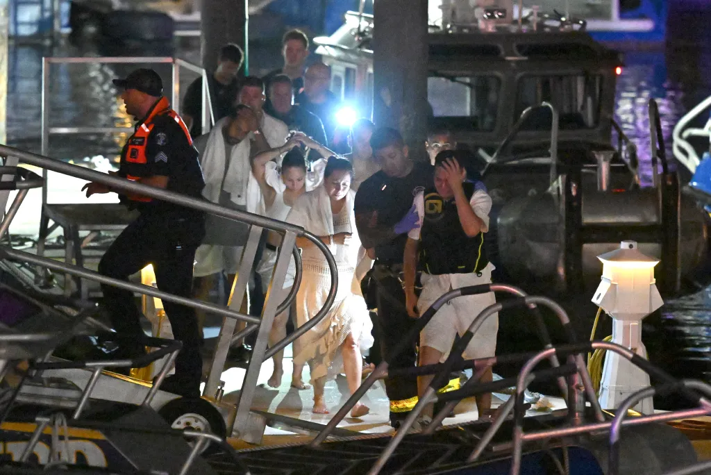 FDNY personnel rescuing victims from a capsized vessel near Liberty Island at night.