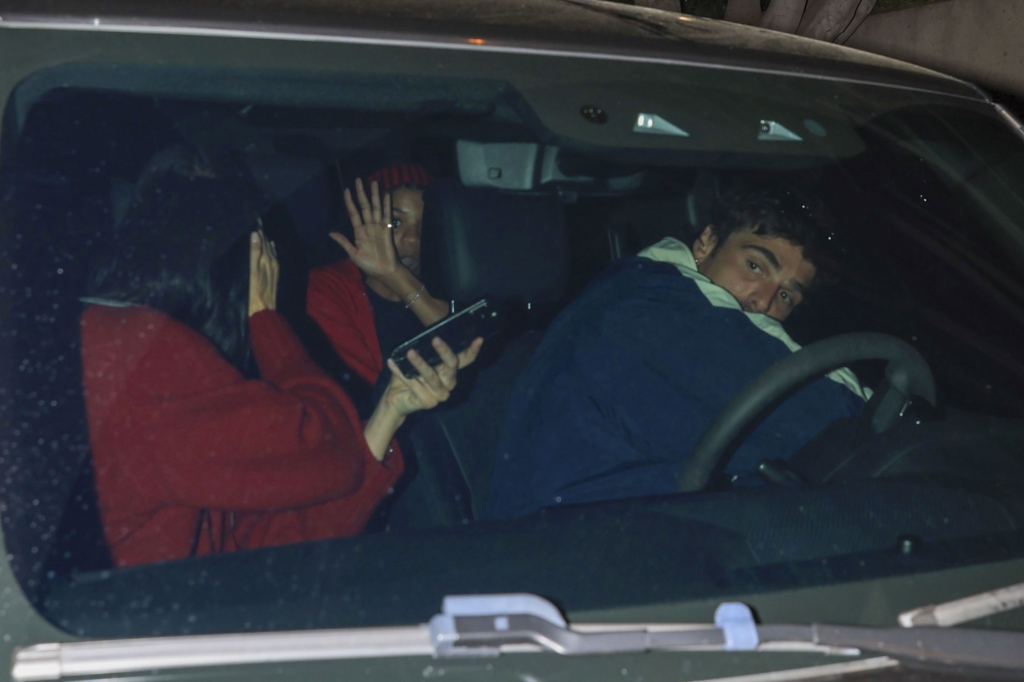 Jacob Elordi driving a car with Kendall Jenner in the passenger seat and two other passengers in the back, one of whom is waving their hand at the camera.