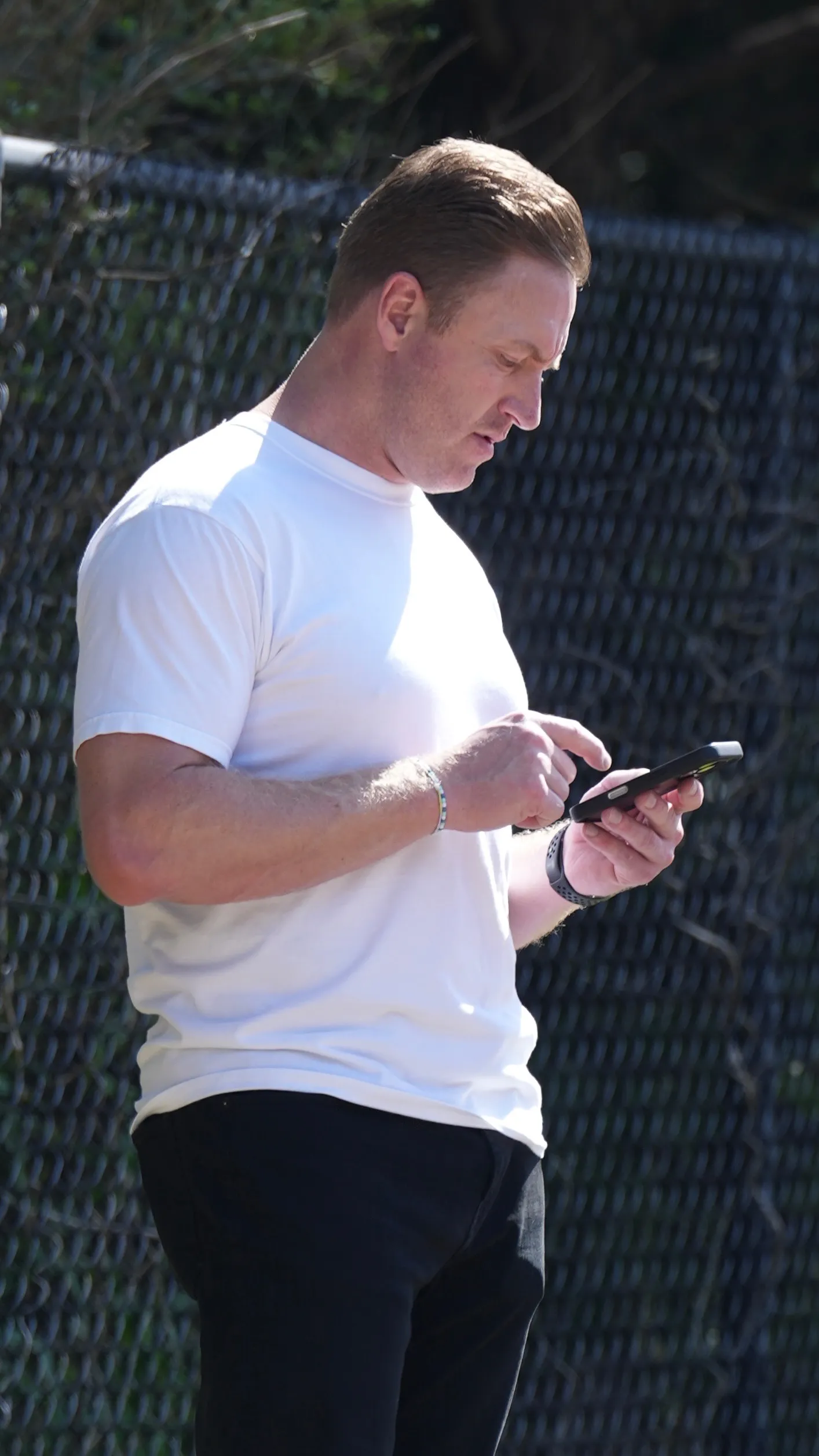 Kroy Biermann looking at his phone while picking up his son from football practice.