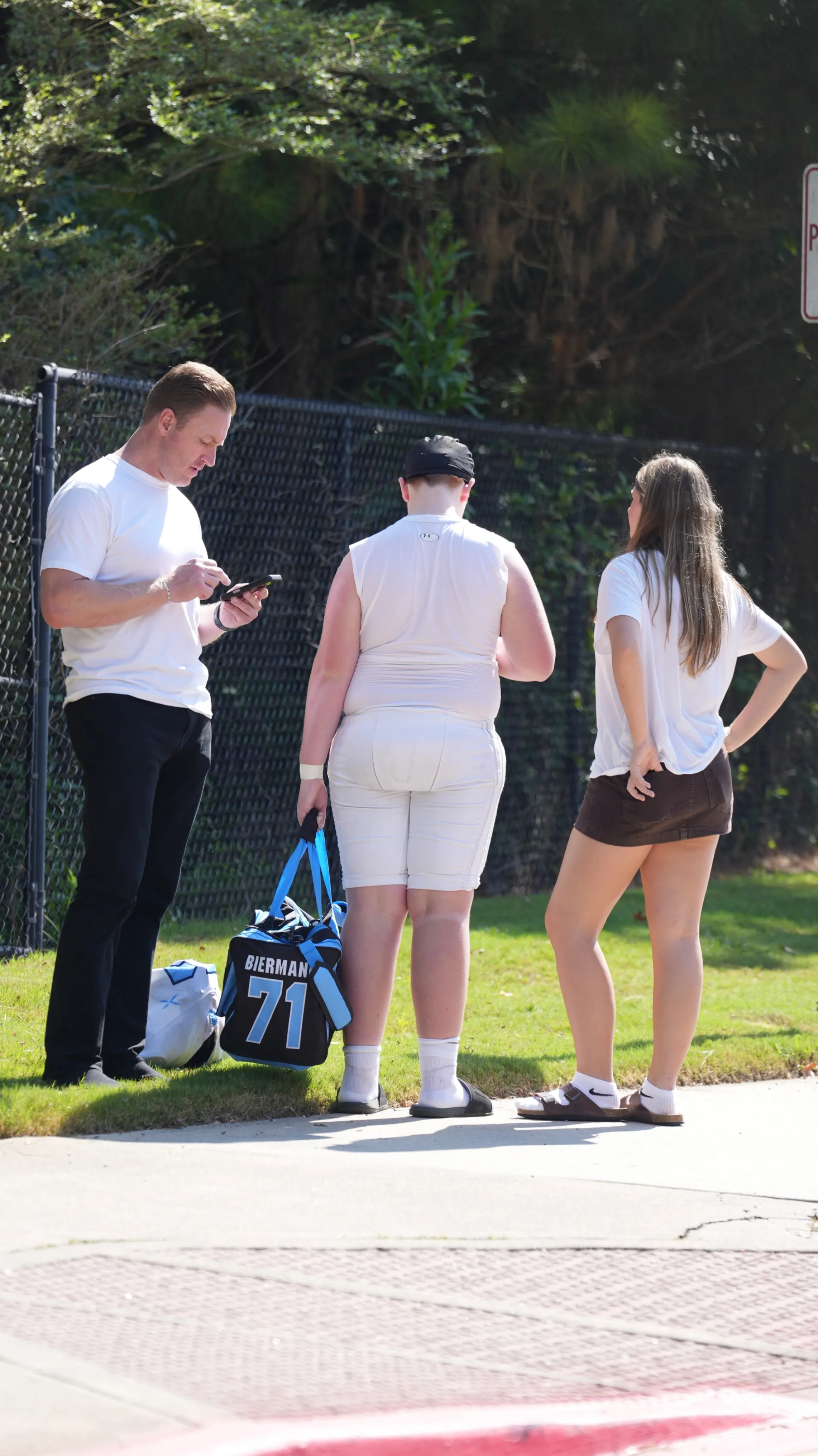 Kroy Biermann looks at his phone while picking up his son from football practice, accompanied by another child.
