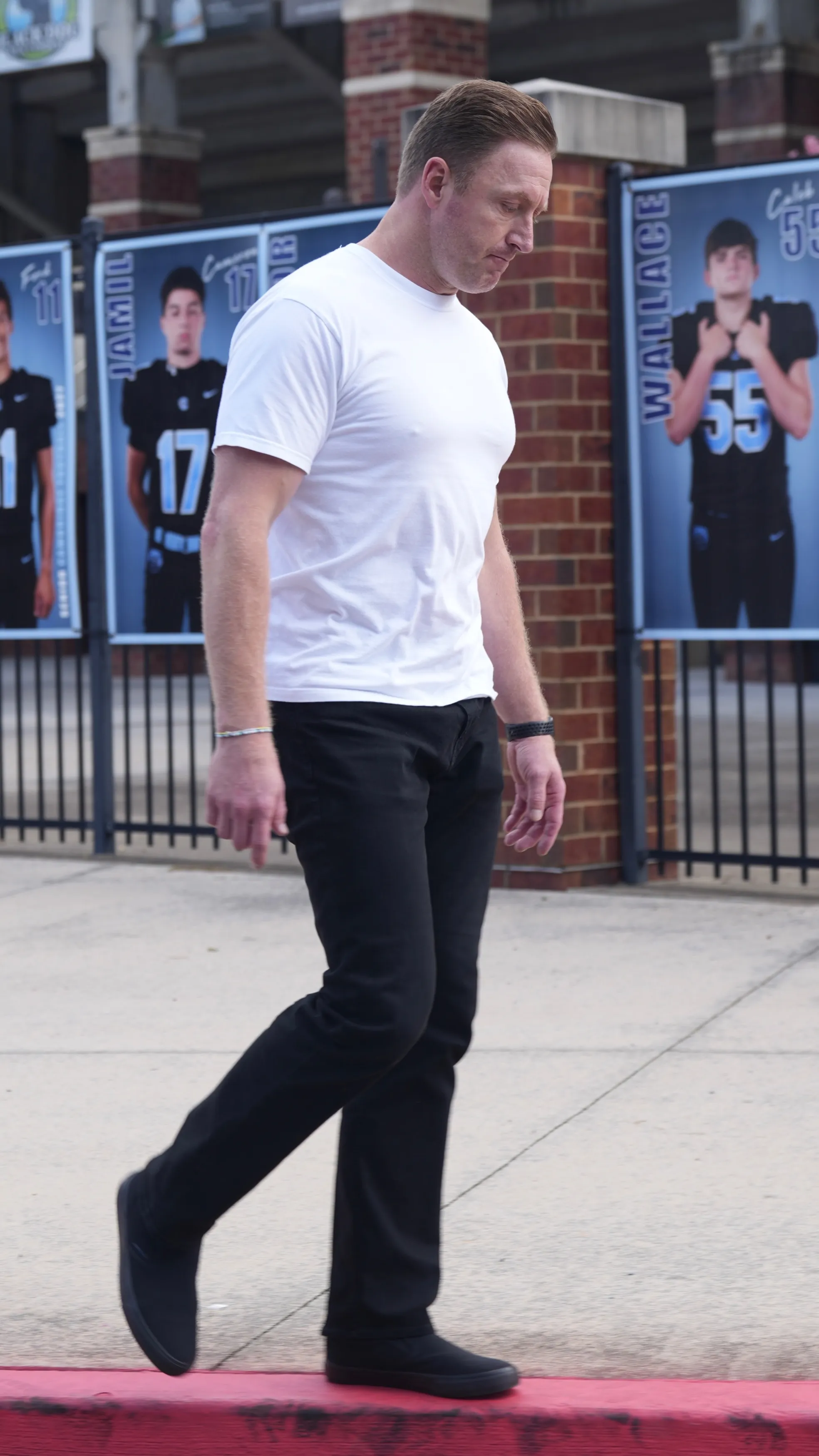 Kroy Biermann walking outside a football field with player posters in the background.