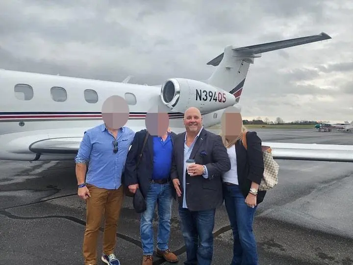 Todd Burkhalter and three other people stand in front of a private jet.