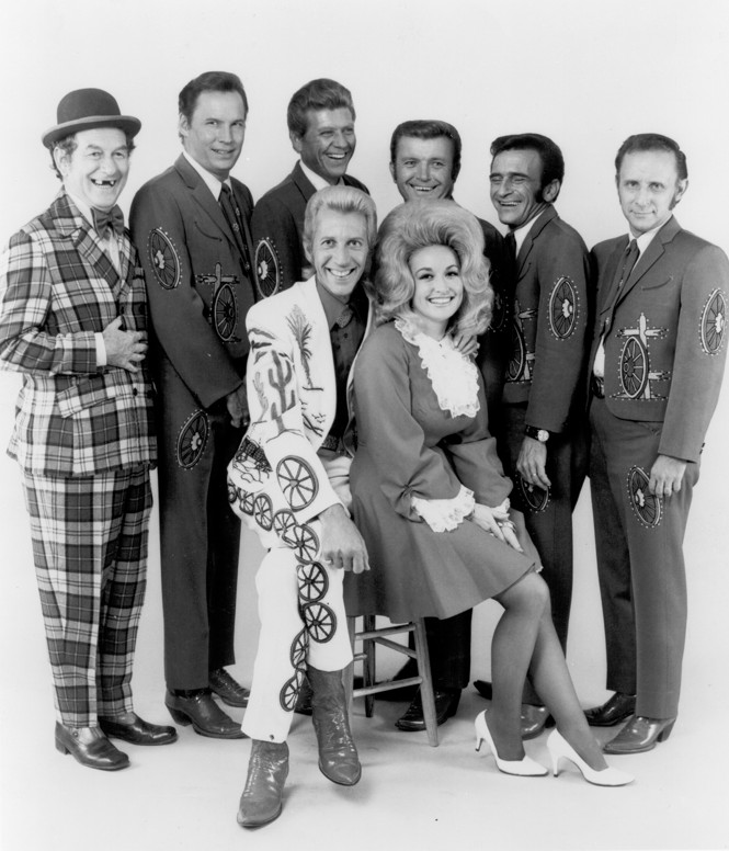 Country singers and collaborators Porter Wagoner and Dolly Parton pose for a portrait with their back up band, 