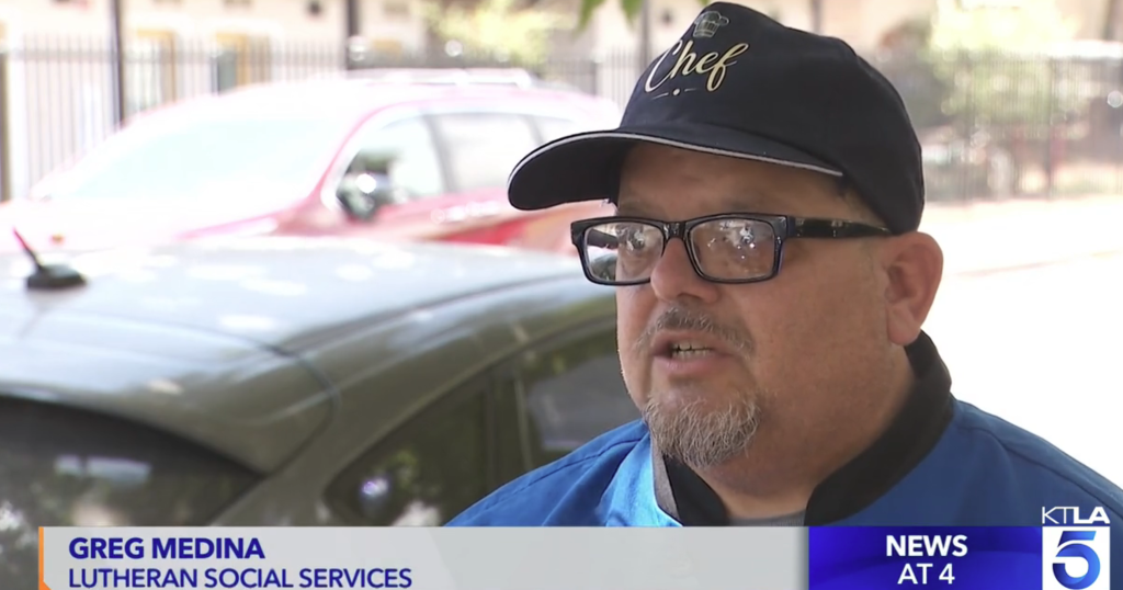 Greg Medina, a 48-year-old man, wearing a chef's hat and glasses, speaks to a reporter.