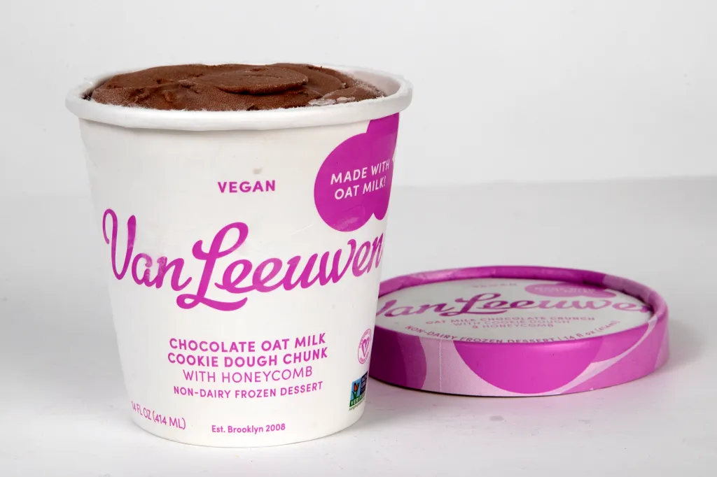 A pint of Van Leeuwen vegan chocolate oat milk cookie dough chunk with honeycomb ice cream next to its lid.