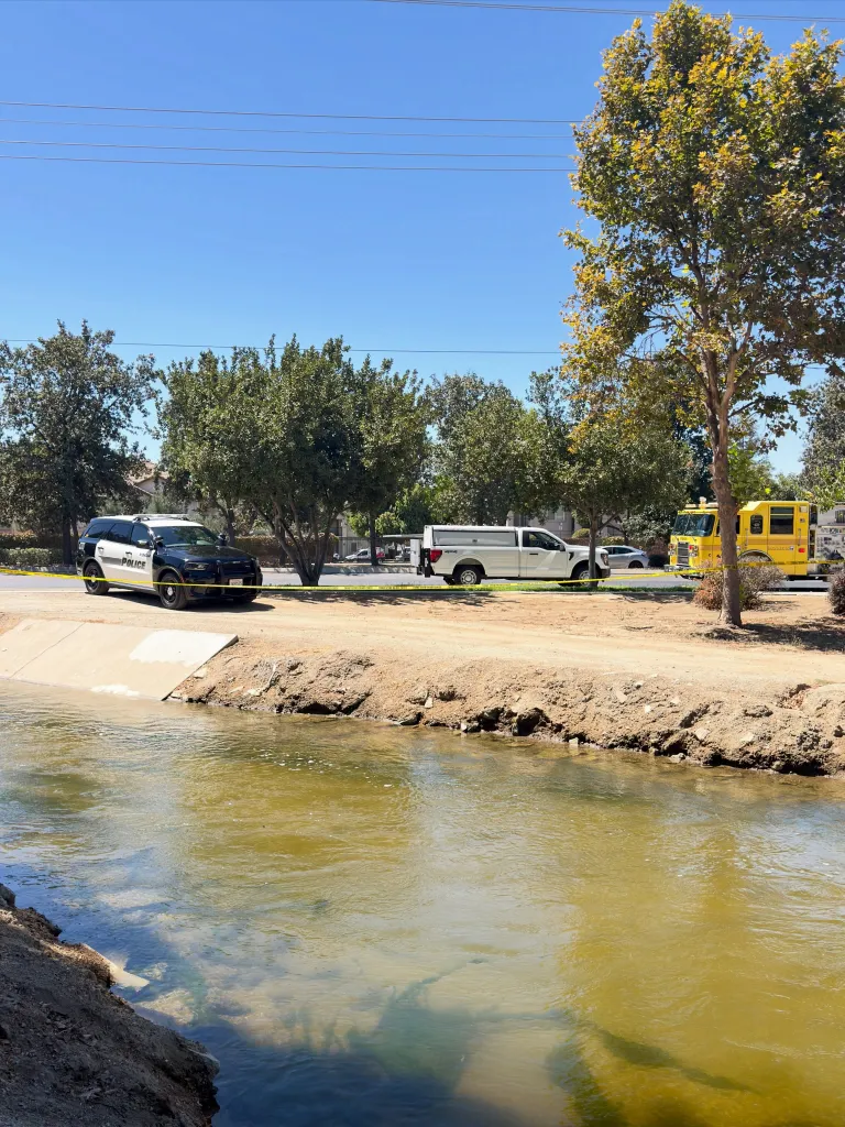 Visalia Police Department and emergency vehicles block off a canal where a body was found.
