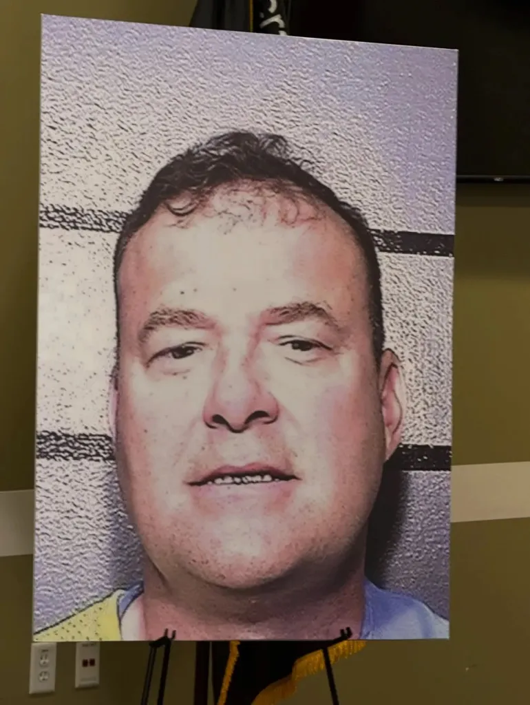 Mugshot of Gregory Lee Vogelsang, 57, a white man with a receding hairline and short dark hair, shown from the chest up.